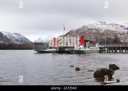 Glenridding, Cumbria, Lake District: Ullswater 'Steamers' Boats Lady of the Lake und Raven moored am Glenridding Pier mit schneebedeckten Fells dahinter. Stockfoto