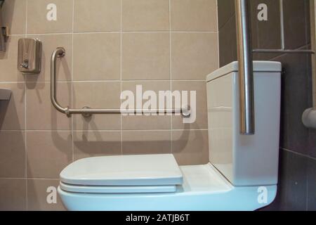 Behindertengerechte toilette mit weißen und grauen Fliesen Stockfoto