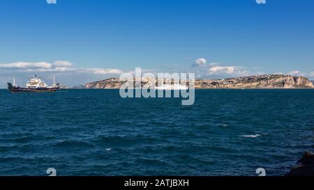 Procida, ITALIEN - 5. JANUAR 2020 - Insel Procida, ein Fährschiff und ein Blick auf den Monte di Procida an einem sonnigen Tag im Winter Stockfoto