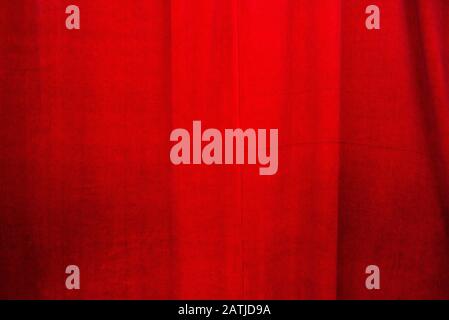 Dunkelrotes Hintergrundmaterial mit weichen Falten und Schmutzflecken bei ungleichmäßigem Kerzenlicht Stockfoto