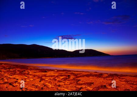 Menschenleerer Strand, Berg, Sonne unterging hinter dem Berg Stockfoto