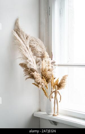 Trockenes Schilf in Keramikvase auf Fensterbank, Vintage-Heim-Innenraum Stockfoto