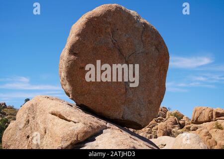 Ein großer Felsbrocken aus Granit, der der Schwerkraft trotzt, klammert sich präkariös an die darunter liegenden Felsen. Stockfoto