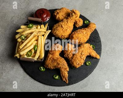 Panierte, knusprige gebratene Hühnerbeine, Flügel, Pommes frites und Sauce Stockfoto