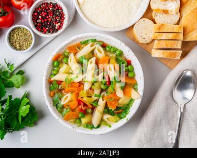 Minestronensuppe, italienische Küche. Vegetarische Suppe mit Gemüse, Penne-Paste und Käse. Weißer Tisch, Draufsicht Stockfoto