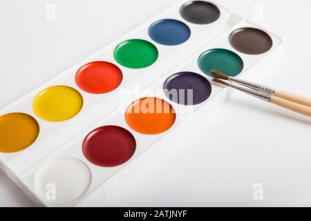 Set mit Aquarellfarben in Kunststoffbox und zwei Bürsten auf weißem Hintergrund Stockfoto