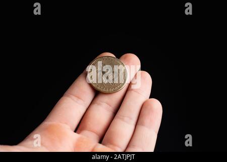 Bitcoin-Münze in einer Hand auf schwarzem Hintergrund. Stock Foto Mann mit einer Münze. Stockfoto