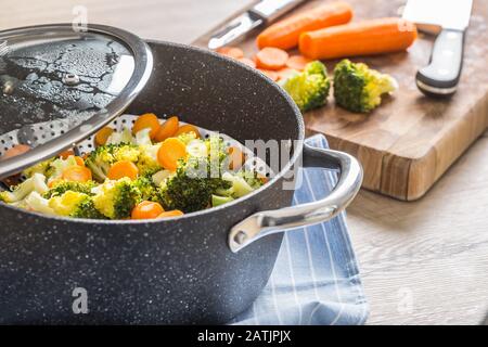 Gedämpftes gemischtes Gemüse in schwarzem Topf. Gesundes Gemüsekonzept Stockfoto