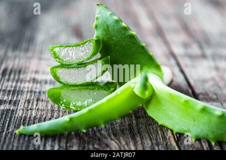 Frische Aloe Vera Blätter und Scheiben von Aloe Vera auf einem Holzhintergrund. Aloe zur Behandlung und Hautpflege. Stockfoto