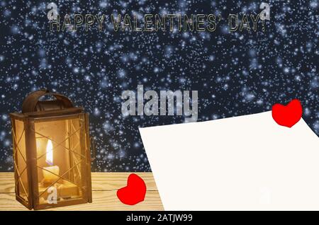 Valentinskarten in Form eines Herzens, eines leeren Papierbogens und einer Laterne, vor dem Hintergrund des Schneefalls. Das Konzept des Valentinstages Stockfoto