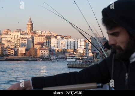 Istanbul, Türkei - 10. Januar 2020: Fischer auf der Galata-Brücke im Stadtteil Eminonu, Galata-Brücke ist im Hintergrund der Stadtteil Beyoglu in Istanbul. Turk Stockfoto