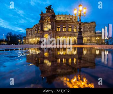 Dresden, Deutschland. Februar 2020. Das Semper-Opernhaus spiegelt sich abends in einer Pfütze auf dem Theaterplatz wider. Kredit: Robert Michael / dpa-Zentralbild / dpa / Alamy Live News Stockfoto