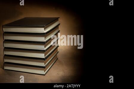 Stapel von Hardcover-Büchern auf braunem Hintergrund, Platz für Text auf der rechten Seite Stockfoto