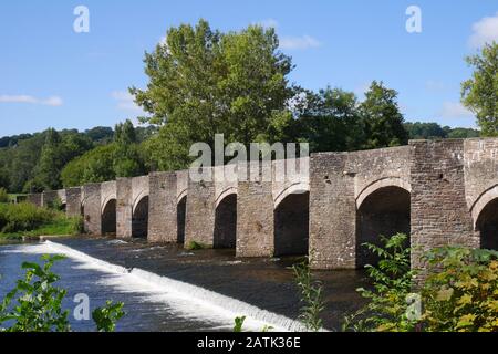 Die Klasse 1 führte eine Brücke aus dem 18. Jahrhundert auf, die über einem Wehr über den Fluss Usk, Crickhowell, Powys, Wales, Großbritannien stand Stockfoto