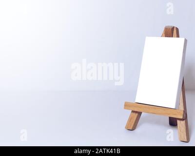 Staffelei für Künstler und leere Leinwandminiatur auf weißem Hintergrund. Stockfoto
