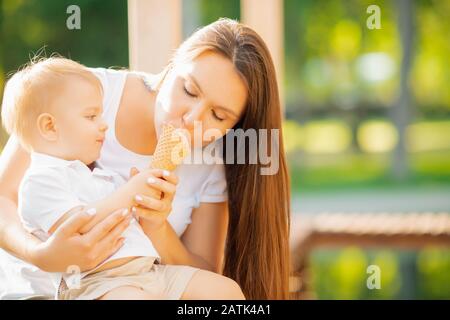 Mutter teilt Eis mit ihrem Babysohn, lächelt und lacht. Sonniger Sommertag Stockfoto