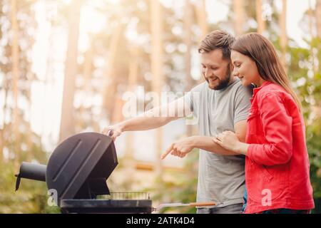 Mann unterrichtet Mädchen Paar beim Kochen von Grillfleisch Stockfoto