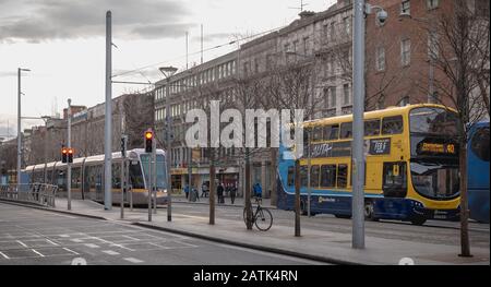 Dublin, Irland - 12. Februar 2019: Typischer irischer Doppeldeckerbus und eine elektrische Straßenbahn mit ihren Fahrgästen im Stadtzentrum im Winter Stockfoto