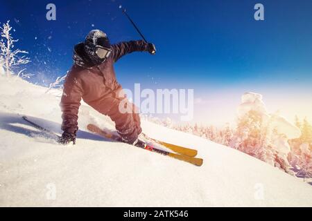 Skifahrer fahren im sonnigen Tag in den Bergen und im Wald bergab. Extrem-Wintersport Stockfoto