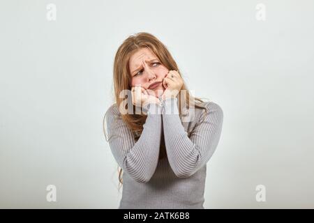 Rothaarige Frau in grauem Pullover rührig enttäuschend das Kinn in den Händen antreiben Stockfoto