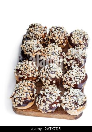 Hausgemachte Profiterolen mit Schokolade und gehackten Nüssen isoliert auf Weiß Stockfoto