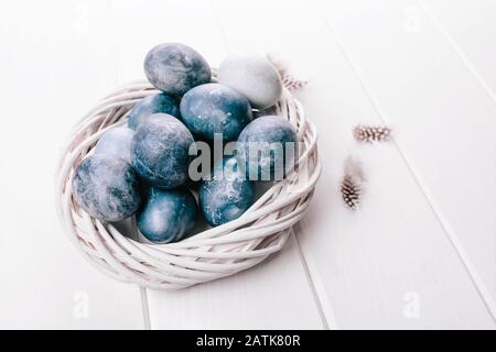 Gruppe hellblauer Eier in ihrem Gelege auf weißem Holzhintergrund. Fröhliche Osterdekoration. Klassische blaue Farbe des Jahres 2020 Stockfoto