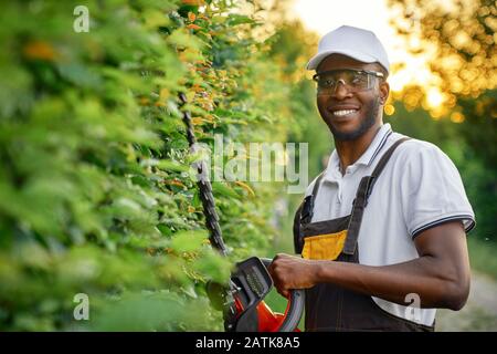 Der Gärtner trägt einen Schutzanzug und mäht Gras in seinem Garten mit