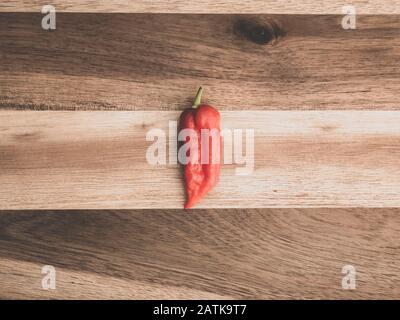 Dekoration von Chilipppern auf Woddenbrett. Ein Bhut jolokia auf Holzhintergrund Stockfoto