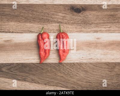 Dekoration von Chilipppern auf Woddenbrett. Zwei Bhut jolokia auf Holzhintergrund Stockfoto