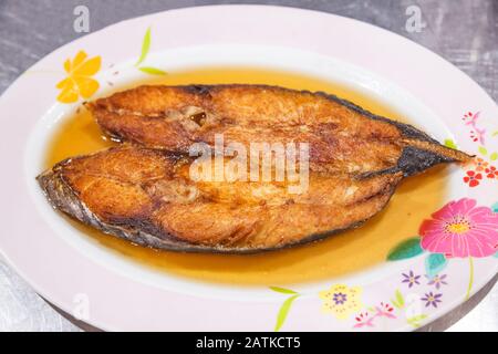 Köstlicher Natürlicher Frischer, Tiefreifer King-Makrelenfisch mit Fischsauce auf weißem Teller mit Tischhintergrund. Thailändische Küche, Asiatische Küche, Thailändische Freizeit Stockfoto