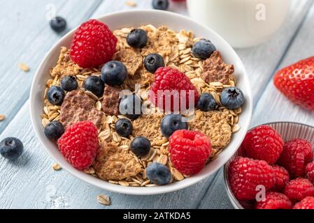 Gesundes Frühstück mit Müsli Chips mit Heidelbeeren und Himbeeren auf weißem Schreibtisch. Stockfoto