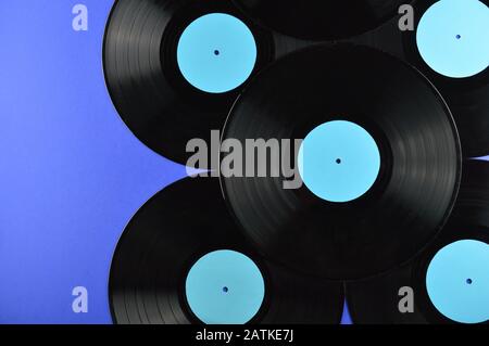 Rahmen alter schwarzer Schallplatten mit leeren zyanblauen Etiketten auf blauem Hintergrund Stockfoto