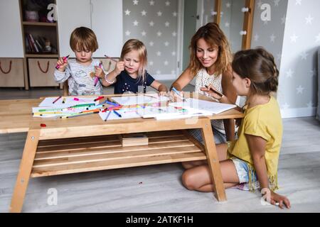 Mama mit kleinen Kindern Zeichnen mit Filzstiften Stockfoto