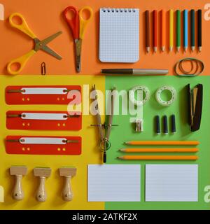 Schulbedarf auf farbenfrohen orangefarbenen, gelben und grünen Pappen auf einem Platz Stockfoto