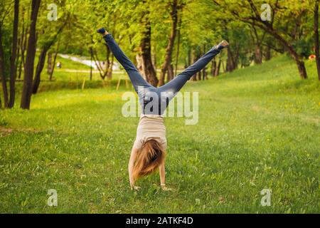 Mädchen macht ein akrobatisches Rad. Auf dem Gras. Stockfoto