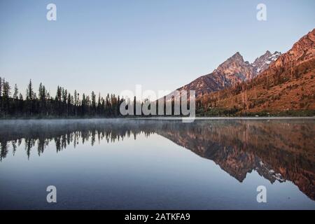 Tetons spiegeln sich bei Sonnenaufgang im stillen Wasser des String Lake Stockfoto