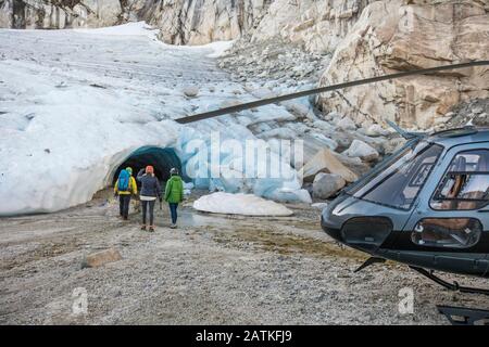 Ein Bergführer nähert sich einer Eishöhle mit Tourkunden. Stockfoto