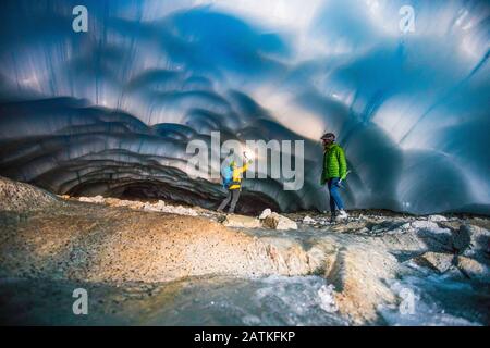 Abenteuerliches Paar, das eine Eishöhle erkundet. Stockfoto