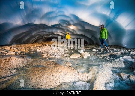 Abenteuerliches Paar, das eine Eishöhle erkundet. Stockfoto