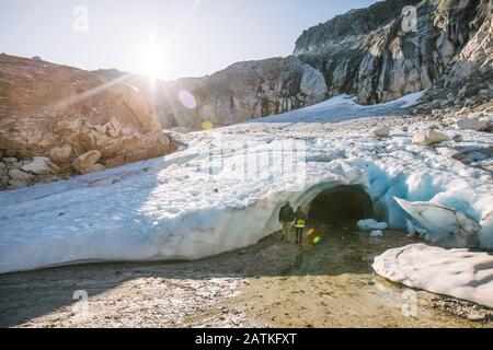 Ein pensionierter Pärchen betritt die Eishöhle während einer luxuriösen Abenteuertour. Stockfoto