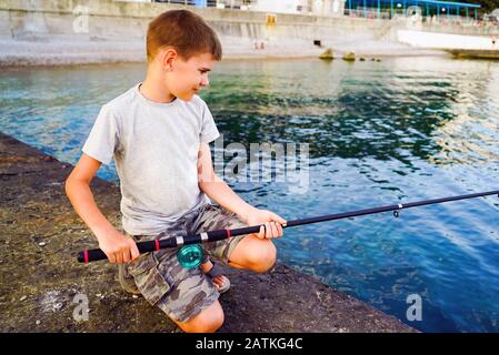 Ein Junge mit Angelrute fängt Fische vom Pier im Meer. Krim. Jutta. Stockfoto