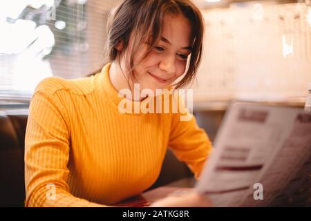 Fröhliches Teenager-Mädchen, das im Café auf die Speisekarte schaut Stockfoto