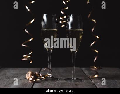 Zwei Gläser Champagner auf Holztisch mit schwarzem Hintergrund. Stockfoto