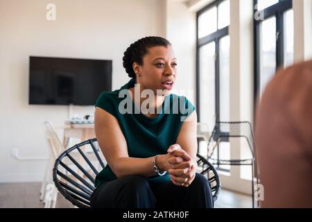 Junge Geschäftsfrau, die mit Händen saß, klaffte bei einem Treffen im Büro Stockfoto