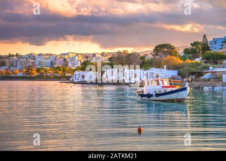 Kleiner natürlicher Hafen mit Fischerbooten verankert mit der schönen Stadt Agios Nikolaos im Hintergrund, Kreta, Griechenland. Stockfoto