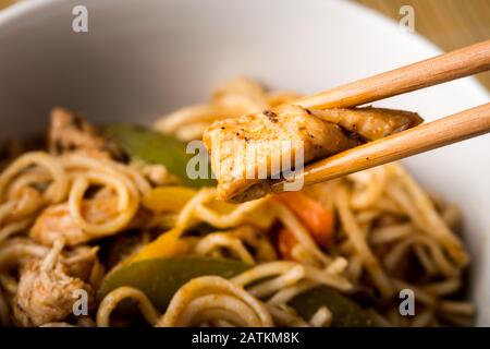 Getrocknete chinesische Nudeln mit Fleisch im Gericht. Bambusstäbchen. Asiatische Küche. Stockfoto