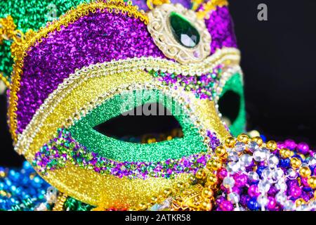 Nahansicht einer Festivalmaske von der Vorderseite aus. Auf ein Bett mit Perlen gelegt. Stockfoto