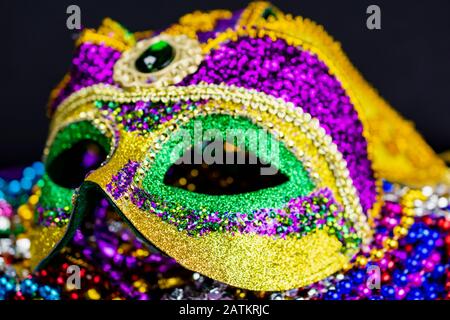 Nahansicht einer bunten Jester-Maske. Selektive Fokussierung auf die Vorderkante der Maske, die in Unschärfe fällt. Dunkler Hintergrund. Querformat Stockfoto