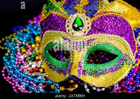 Nahansicht einer bunten Jester-Maske auf einem Perlenbett. Selektiver Fokus auf Augen. Schwarzer Hintergrund. Stockfoto