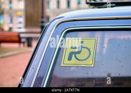 Schild eines Mannes in einem Sessel - behinderter Mensch an der Heckscheibe eines Autos. Nahaufnahme. Stockfoto